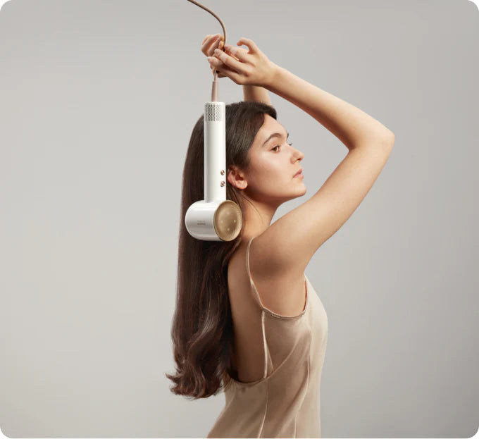 Woman with long hair holding white Dreame hair dryer